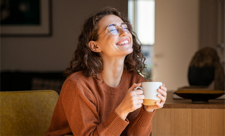 Cheerful woman enjoying coffee cup in a winter afternoon